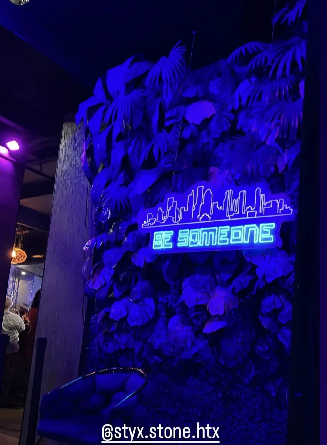 "Be Someone" Houston skyline neon over the floral wall at Styx + Stone
