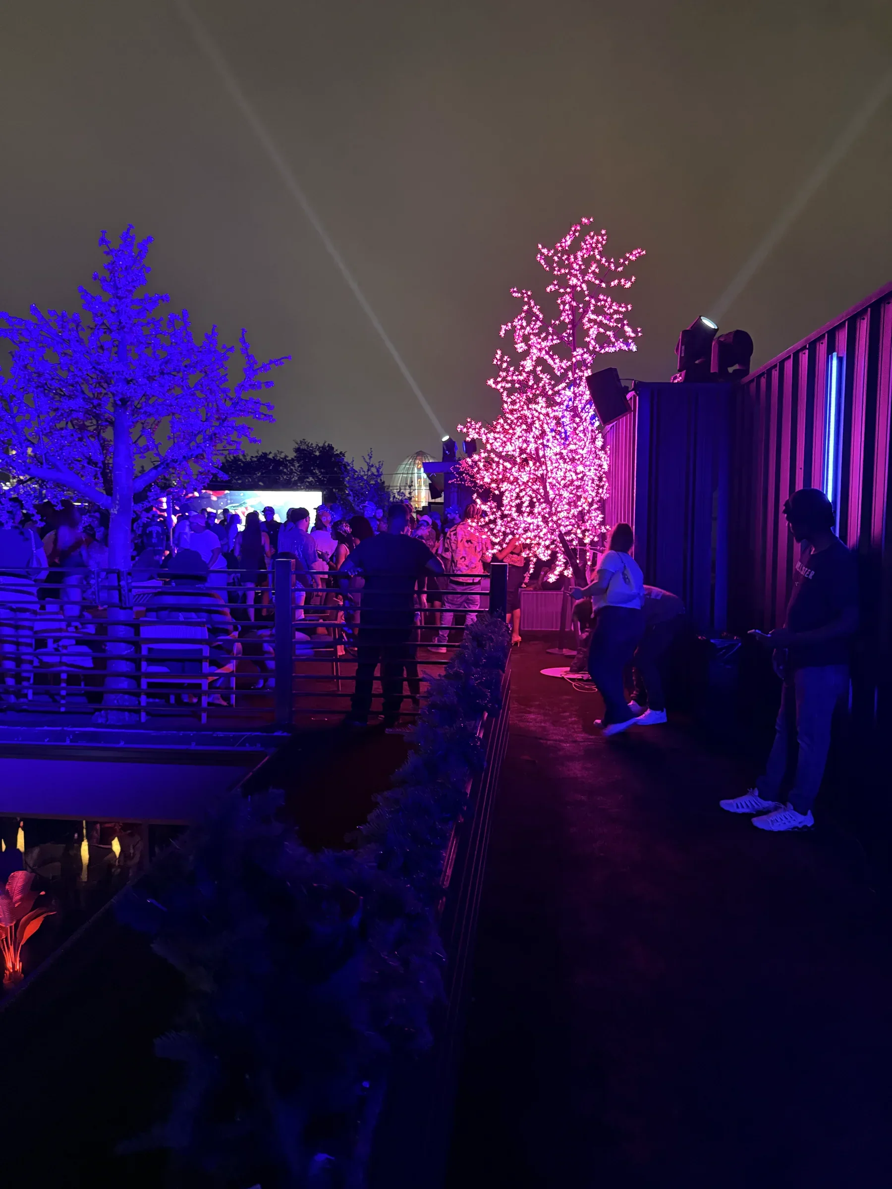 The Styx + Stone rooftop glowing pink at night with the Houston skyline beyond it