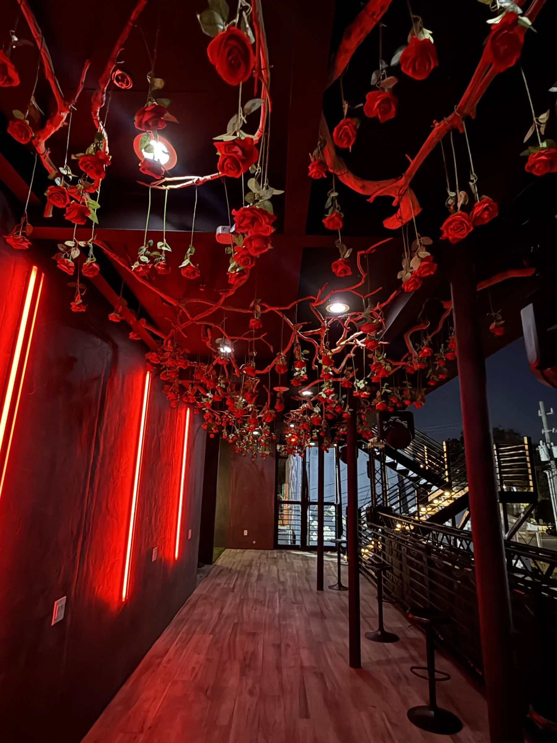 The rose chandelier over the second-floor red neon walkway at Styx + Stone