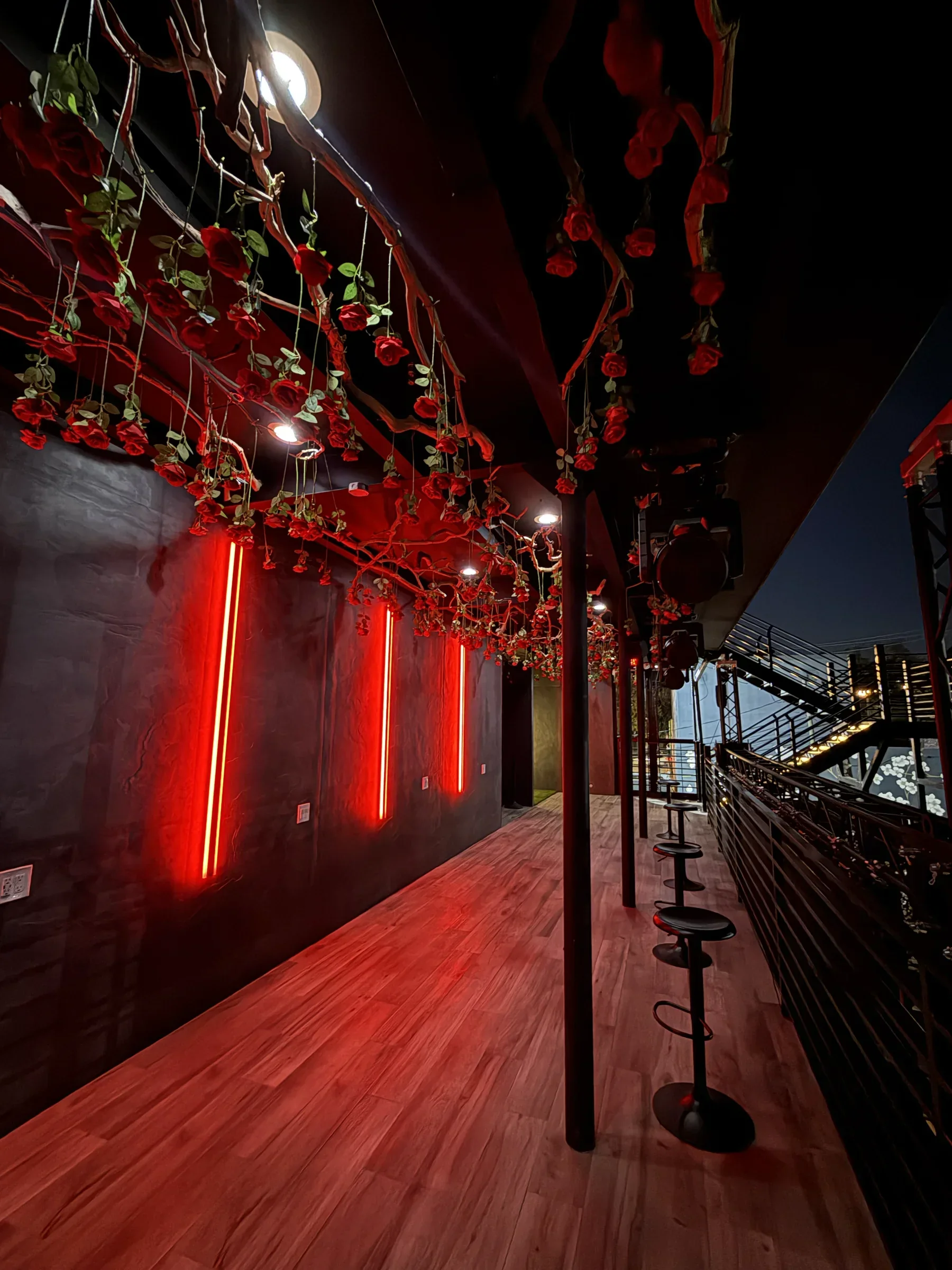 The rose-lined red neon walkway along the second-floor rail at Styx + Stone