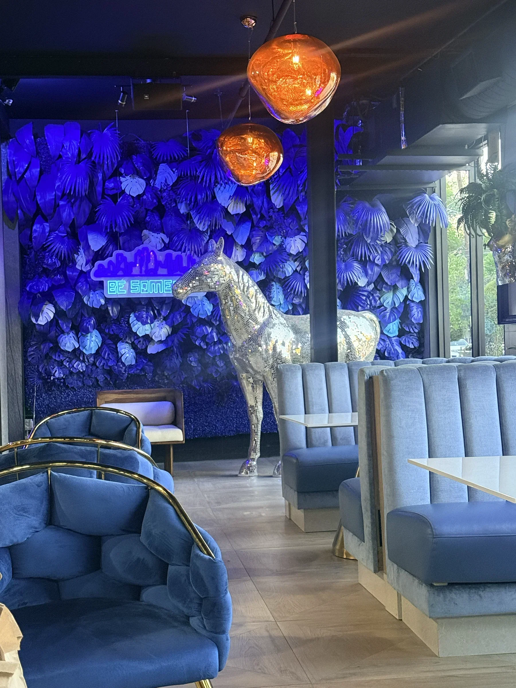 Silver horse sculpture over blue velvet booths in the ground-floor bar at Styx + Stone